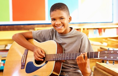 Child with a smile holding a guitar