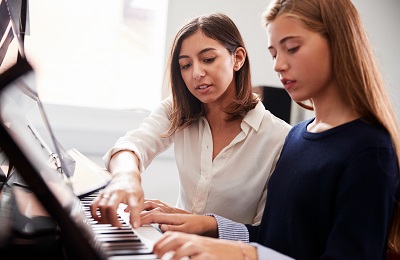 Piano teacher and student sitting at a piano